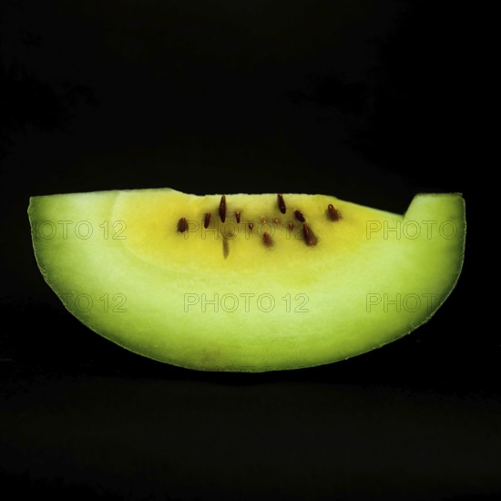 A vibrant slice of watermelon sits against a sleek black background, showcasing its juicy red flesh and contrasting green rind. This refreshing fruit symbolizes summertime and healthy eating