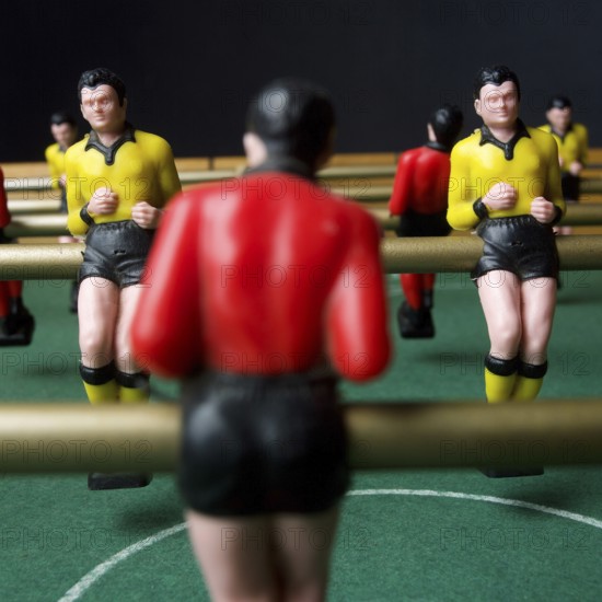 Engaged players immerse themselves in a lively tabletop football game, surrounded by vibrant player figures in yellow and red. Tension and excitement fill the air