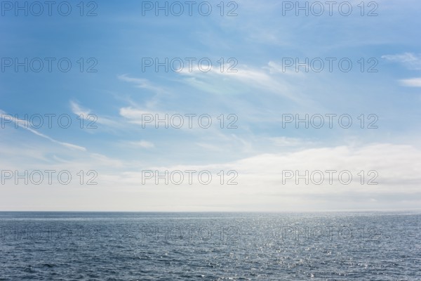Dark ocean under a clear blue sky with bright white feathery clouds, cloud bank, horizon, water with light reflections, dark blue, light, reflection, sunny, water surface, summer, sunny, weather, calm sea, vastness, horizon, landscape, maritime, nature, relaxation, recreation, sunlight, freedom, sea voyage, too: threatening emptiness, being lost, infinite, infinity, nobody, alone, loneliness, journey with the Halunderjet from Heligoland to Hamburg, German Bight, North Sea, Germany