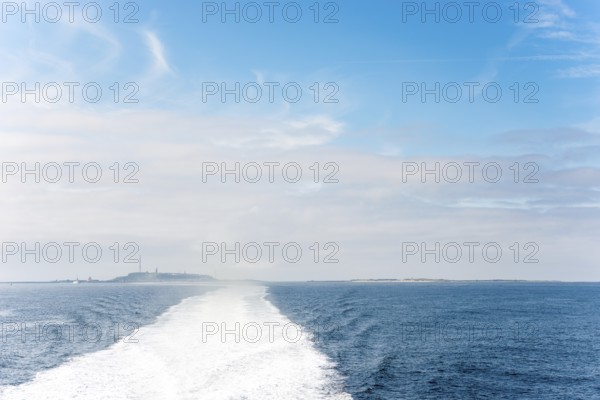 Wide boat track, water track, foam track leading towards the islands of Heligoland (main island and dune) visible on the horizon, track of the ferry Halunderjet to Hamburg, foam and haze, churning water behind the catamaran, high speed, high speed, speedboat, high speed, ship, boat, motorboat, bow waves, blue sky, feather clouds, cloud bank on the horizon, dark blue, ocean, water surface, summer, sunny weather, calm sea, German Bight, North Sea, Germany
