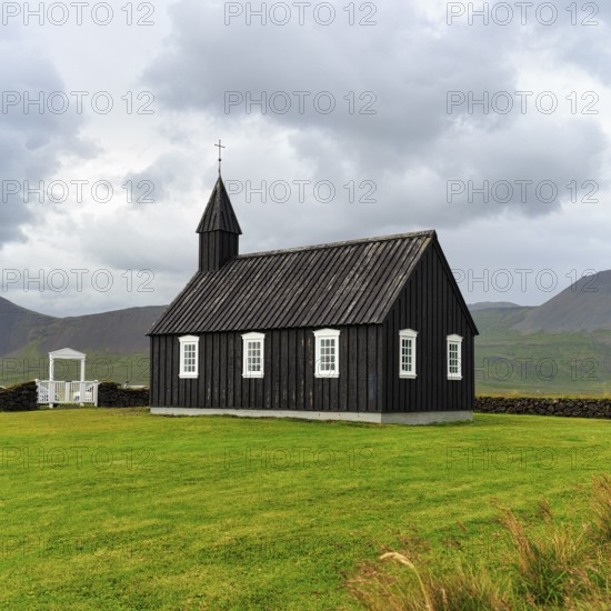 Traditional black church with white Tor tor in a meadow, wooden church Budakirkja, Búðir, Budir, Snaefellsnes Peninsula, Iceland
