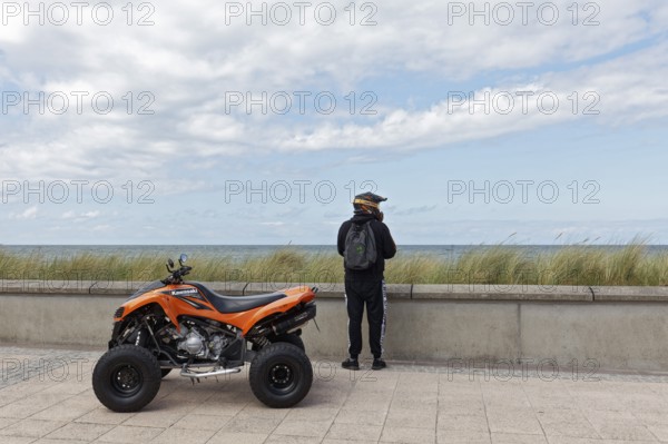 Motorcyclist with Kawasaki Quad Bike on the beach promenade, looking at the sea, Baltic resort Kühlungsborn, Baltic Sea, Mecklenburg-Vorpommern, Germany