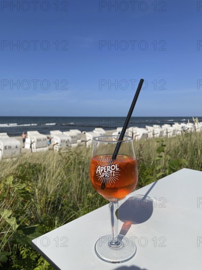 Glass of Aperol Spritz on a table overlooking the beach, Baltic resort Kühlungsborn, Mecklenburg-Vorpommern, Germany