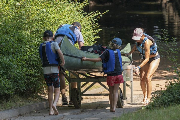 Family pushes canoe with canoe cart to the Alte Fahrt canal, Bolter Mühle, Mecklenburg Lake District, Mecklenburg-Western Pomerania, Germany