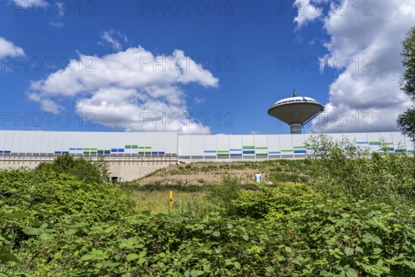 Green corridor with the river Dhünn, 40 km long river that flows into the Wupper near Leverkusen, renaturalised section, here shortly in front of the mouth along the A1 motorway, at the Leverkusen-West junction, noise barrier, landmark Leverkusen water tower, North Rhine-Westphalia, Germany