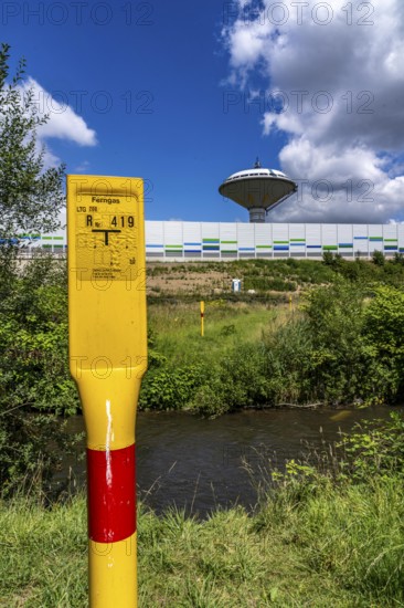 Marker post for a long-distance gas pipeline on the river Dhünn, 40 km long river that flows into the Wupper near Leverkusen, renaturalised section, here shortly in front of the mouth along the A1 motorway, at the Leverkusen-West junction, noise barrier, landmark water tower Leverkusen, North Rhine-Westphalia, Germany