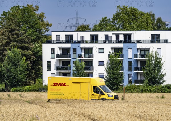DHL parcel van, electric vehicle, on the way to a customer, rural, driving along a dirt track through a corn field, North Rhine-Westphalia, Germany