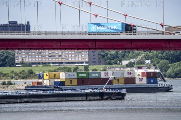 Barges on the Rhine at Ruhrort harbour, container freighter on uphill journey, Friedrich-Ebert-Bridge, road bridge over the Rhine between Homberg and Ruhrort, Maersk container on lorry on the bridge, Duisburg, North Rhine-Westphalia, Germany
