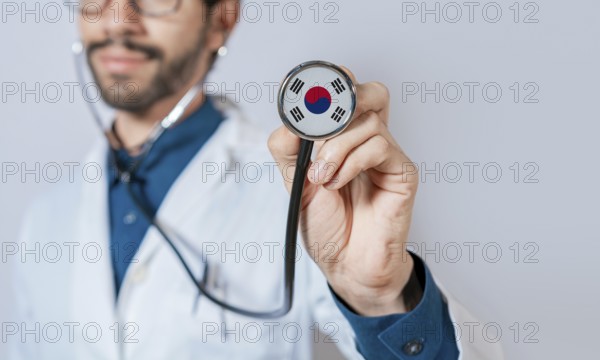 Doctor holding stethoscope with South Korea flag. South Korea health and care concept, South Korea flag on stethoscope
