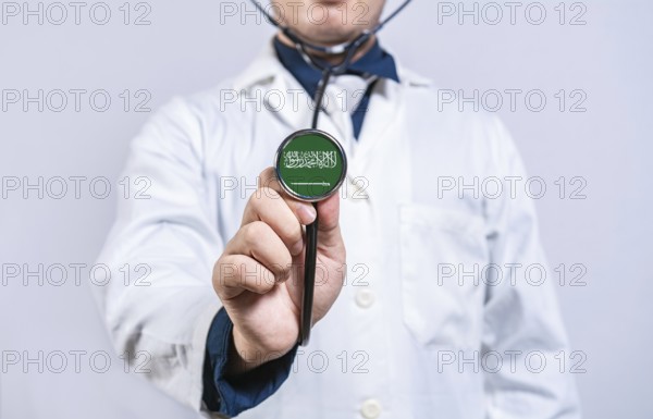 Doctor hands holding stethoscope with Saudi Arabia flag. Saudi Arabia health and care concept