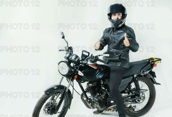 Smiling motorcyclist on his motorcycle with thumbs up, isolated. Motorcyclist with helmet on his motorcycle with thumbs up isolated