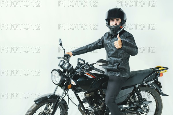 Male motorcyclist on his motorcycle with thumbs up on an isolated background. Smiling motorcyclist on his motorcycle with thumbs up isolated