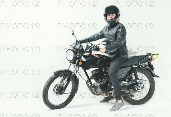 Male motorcyclist riding his motorcycle on isolated background. Smiling young man riding a motorcycle, looking at the camera