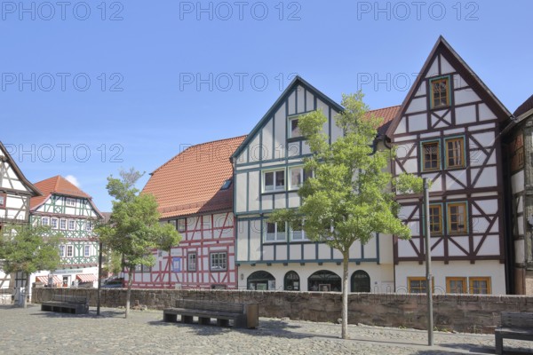 Colourful half-timbered houses, red, green, brown, empty benches, churchyard, Schmalkalden, Franconia, Thuringia, Germany