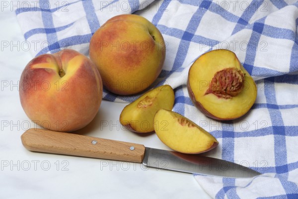 Peach with knife on kitchen towel, peach halves, Prunus persica
