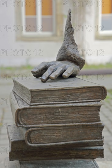 Monument to merchant, publicist and publisher Carl Joseph Meyer, sculpture, modern art, pile of books with hand on book, fingers, books, stacked, Hildburghausen, Franconia, Thuringia, Germany