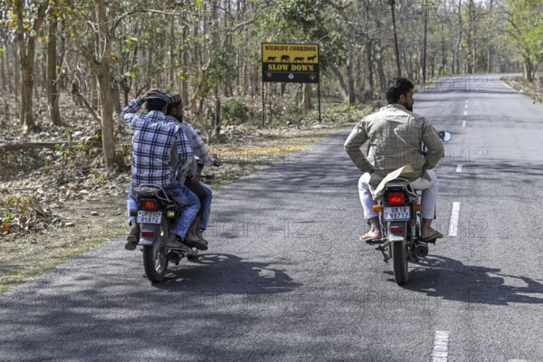 Motorcyclist in front of a Wildlife Corridor sign, Corbett National Park, near Ramnagar, Uttarakhand State, India