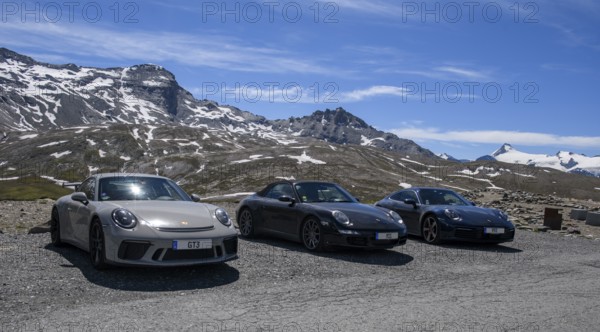 Three Porsche 911 sports cars parked on an Alpine road above the tree line, 911 991 GT3 on the left, 911 997 Carrera 4s in the centre, 911 992 Carrera 4s on the right, Col de l'Iseran pass, departmental road D902, Route des Grandes Alpes, Département Savoie, Auvergne-Rhône-Alpes region, Graian Alps, France