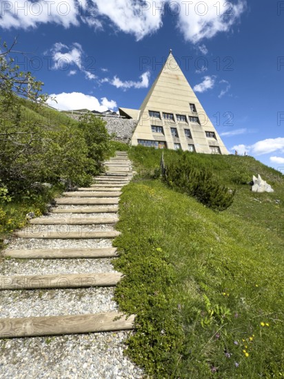 View of museum Musée Museo Mont-Cenis Pyramid Museum in stylised pyramid as museum to commemorate Egyptian campaigns of Emperor Napoleon Bonaparte and time in front of construction of reservoir, left staircase of Jardin Alpin, Mont Cenis massif, Massif du Mont-Cenis, Graian Alps, Lanslebourg, Rhone-Alpes, France