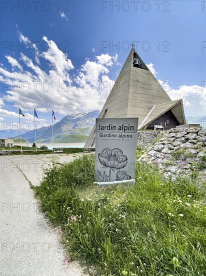 In front sign for Jardin Alpin, behind it pyramid museum with stylised pyramid in memory of the Egyptian campaigns of Emperor Napoleon Bonaparte and the time in front of the construction of the Lac du Mont Cenis reservoir, Mont Cenis massif, Massif du Mont-Cenis, Graian Alps, Lanslebourg, Rhone-Alpes, France