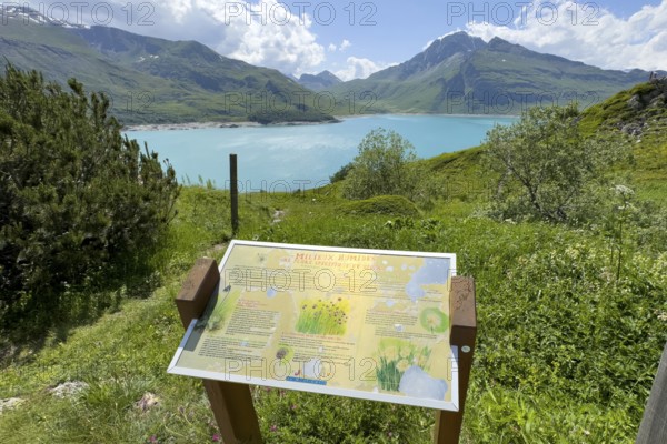 In the foreground information board with explanations about Jardin Alpin, in the background Lac du Mont Cenis reservoir, Mont Cenis massif, Massif du Mont-Cenis, Graian Alps, Lanslebourg, Rhone-Alpes, France