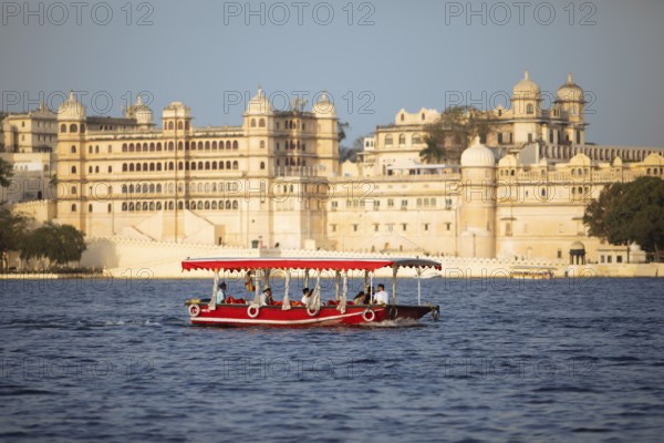 Excursion boat on Lake Pichola, behind the City Palace in the evening light, Udaipur, Rajasthan, India