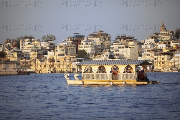 Excursion boats on Lake Pichola, behind the old town in the evening light, Udaipur, Rajasthan, India