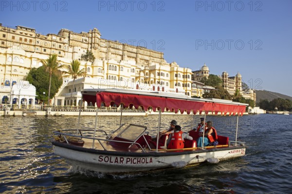 Excursion boat on Lake Pichola, behind the City Palace in the evening light, Udaipur, Rajasthan, India
