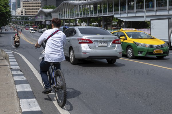 Road traffic cyclists and cars, Bangkok, Thailand