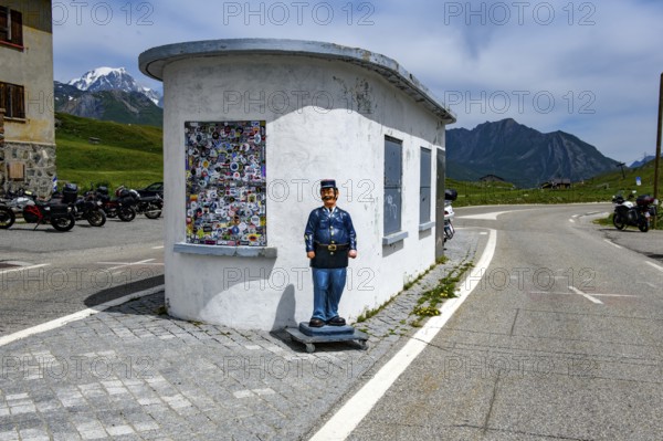 Disused former border house for passport control at the border crossing between France and Italy, in front of it a figure of a French border official, Graian Alps, Département Savoie, France, Valle d'Aosta, Italy