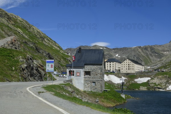 View of historic Swiss border building in the foreground Former passport control checkpoint Passport control Border control Customs control Customs at road crossing National border State border between Italy and Switzerland, on the left next to it sign for road users about toll sticker, on the right Lac du Grand St-Bernard, in the background historic building hostel Auberge de l'Hospice at the top of the Great Saint Bernard Pass, Colle del Gran San Bernardo, Col du Grand Saint Bernard, Italy, Switzerland