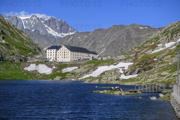 View from Italian side on small island in Lac du Grand Saint Bernard in the background on Swiss territory historic Auberge Herberge Hospice on pass summit of 2473 metres high alpine pass Great Saint Bernard, Saint-Rhémy-en-Bosses, region Valle d'Aosta, Italy