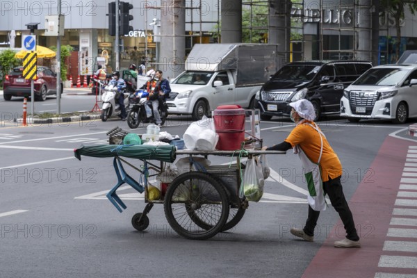 Street crossing woman with cookshop, Bangkok, Thailand