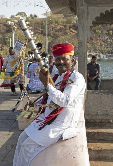 Indian man playing a long-necked spit lute or Ravanahattha at Lake Fateh Sagar, Udaipur, Rajasthan, India