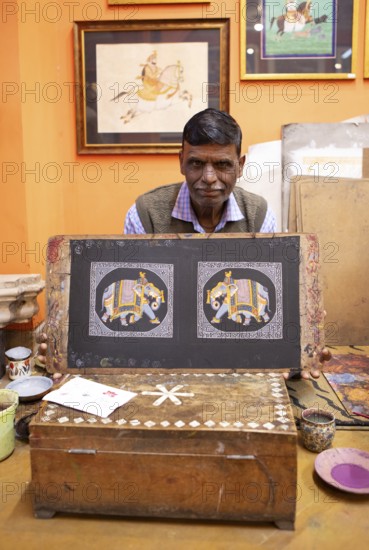 Miniature painter, 52 years old, shows a picture of the royal elephant in his studio, Udaipur, Rajasthan, India