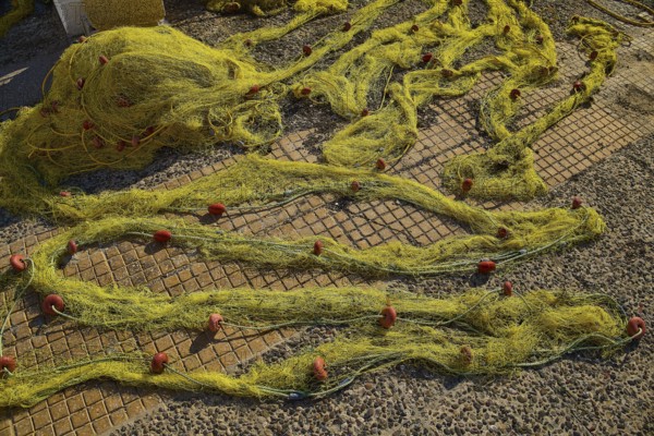 Yellow fishing nets spread on a stony ground on a sunny day, Agia Marina, Leros, Dodecanese, Greek Islands, Greece