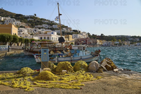 Fishing nets and boats at the harbour with a view of houses on the hillside, Agia Marina, Leros, Dodecanese, Greek Islands, Greece
