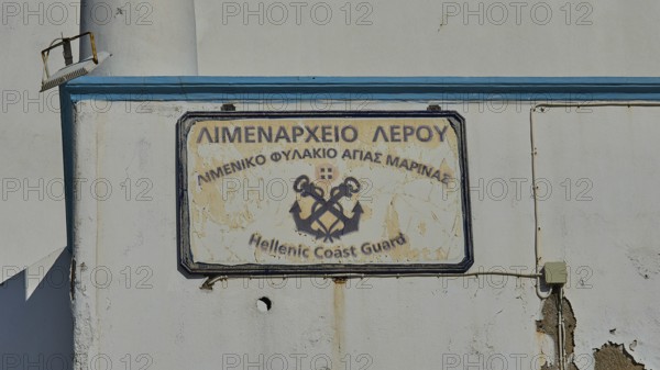 Worn sign of the Hellenic Coast Guard on a white wall, Agia Marina, Leros, Dodecanese, Greek Islands, Greece