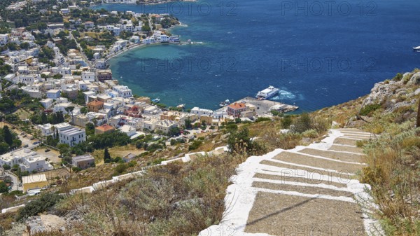 Ormos Alintas, stone path leads to a coastal village with bright blue sea and deep blue sky, Agia Marina, Leros, Dodecanese, Greek Islands, Greece