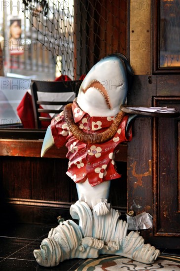 Shark figure with menus on a tray in front of a fish restaurant, New York City, USA