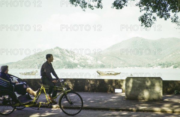 Tricycle rickshaw rider by coastline, Avenida da Republica, Macau, Asia 1964 now Sai Van Lake, Lago Sai Van