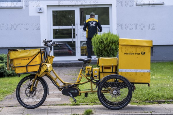 Postman, Deutsche Post, distributes the mail in an apartment building, electric tricycle, North Rhine-Westphalia, Germany