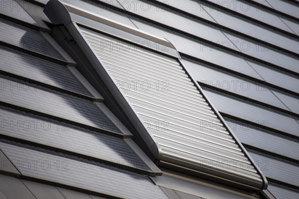 Roof window with roller shutter on a roof covered with solar tiles