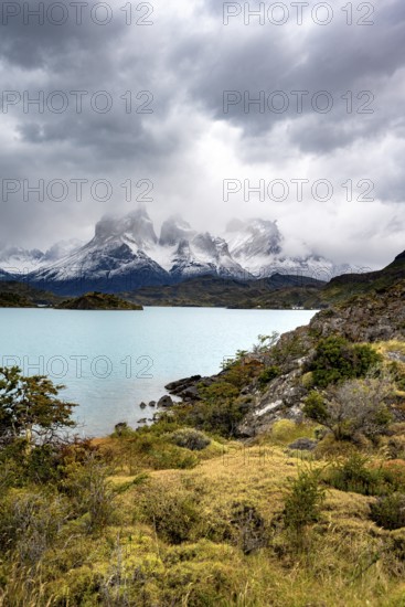 Cloudy mountain range Cuernos del Paine, shore of the blue lake Lago Pehoe in the evening light, dramatic sky, Torres del Paine National Park, Chile