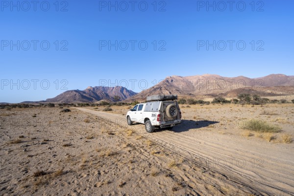 Off-road vehicle on a sandy track, desert landscape with Brandberg, Erongo, Damaraland, Namibia