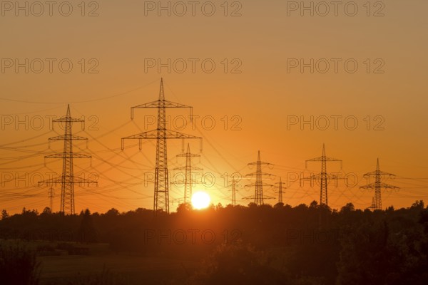 Electricity pylons in front of a glowing sunset on the horizon, Waiblingen, Baden-Württemberg, Germany