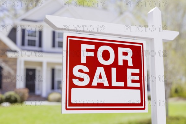 For sale real estate sign in front of beautiful house