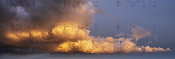 Background image for sky replacement, evening sky with dramatic illuminated dark clouds at sunset, thunderstorm sky
