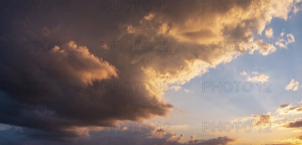 Background image for sky replacement, evening sky with illuminated dark clouds at sunset