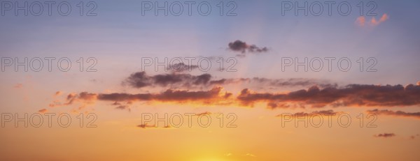 Wallpaper for sky replacement, evening sky with orange glowing clouds and sun rays at sunset